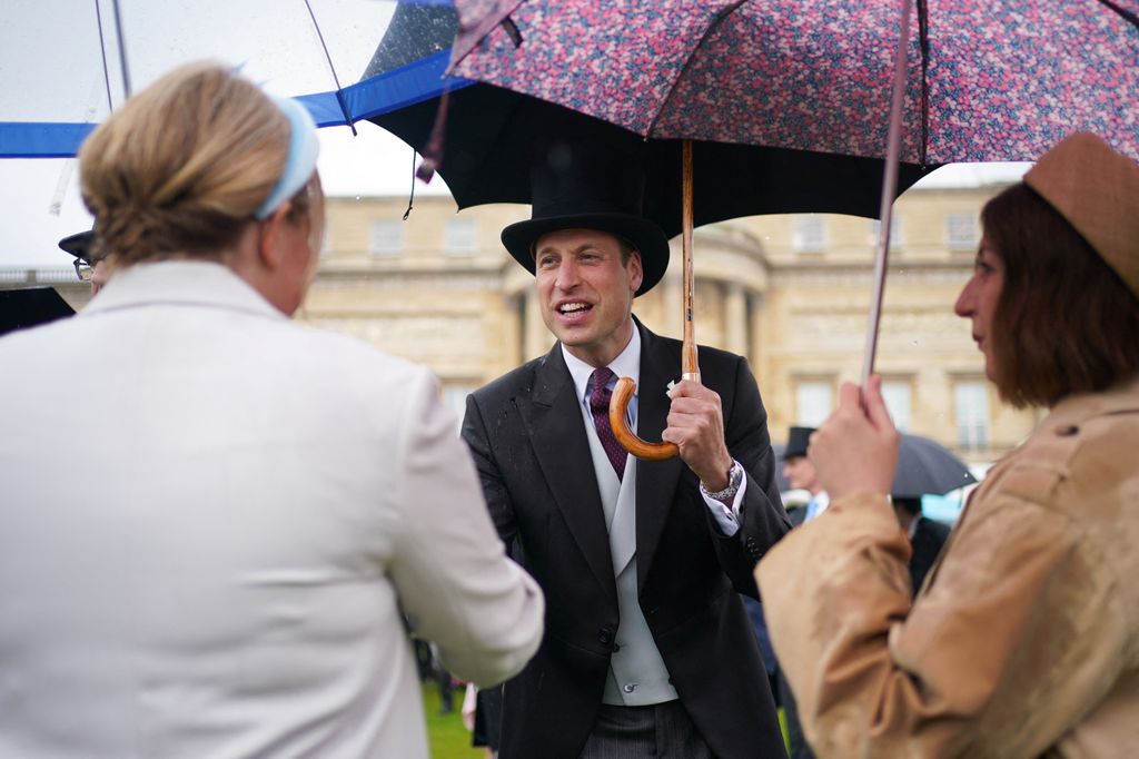 Prince William smiles as he shakes hands with a guest at Buckingham Palace