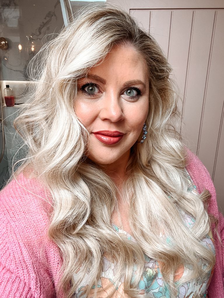 Selfie of blonde woman wearing a pink cardigan