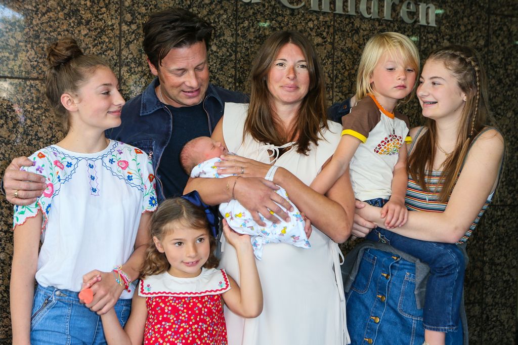 Jamie Oliver and Jools Oliver and children pose with the youngest child outside Portland Hospital