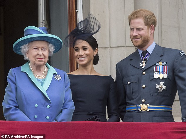 Queen Elizabeth II smiles next to Harry and Meghan on the balcony of Buckingham Palace in 2018