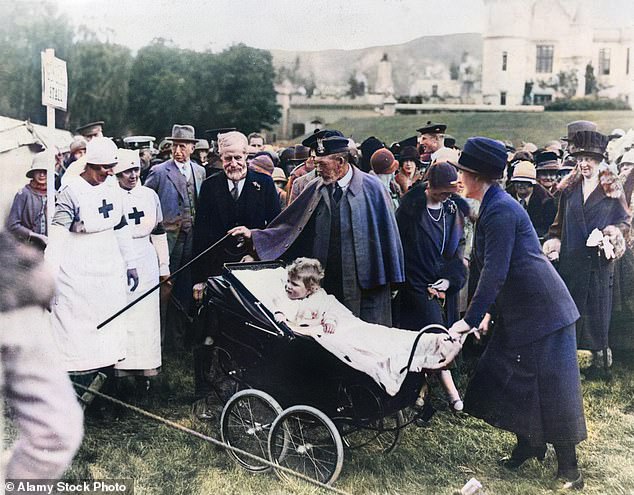 The future Queen Elizabeth II is pushed in a carriage by her maternal grandmother Clara Knight and accompanied by her grandfather King George V