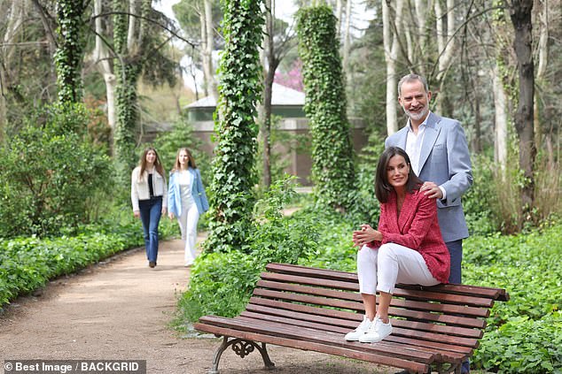In a more artistic pose, Letizia sits on a bench with her husband, while the couple's daughters are seen in the distance