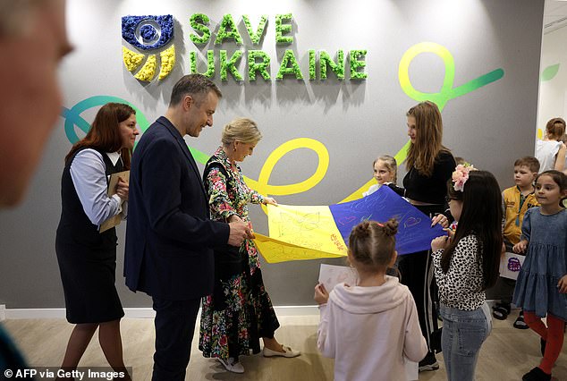 Sophie and children look at the Ukrainian flag while visiting the Family Center Save Ukraine in the city of Irpin on April 29, 2024