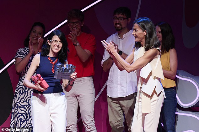 Wearing a sleeveless statement top featuring a woven design in white and cream, Letizia looked delighted as she clapped the winner