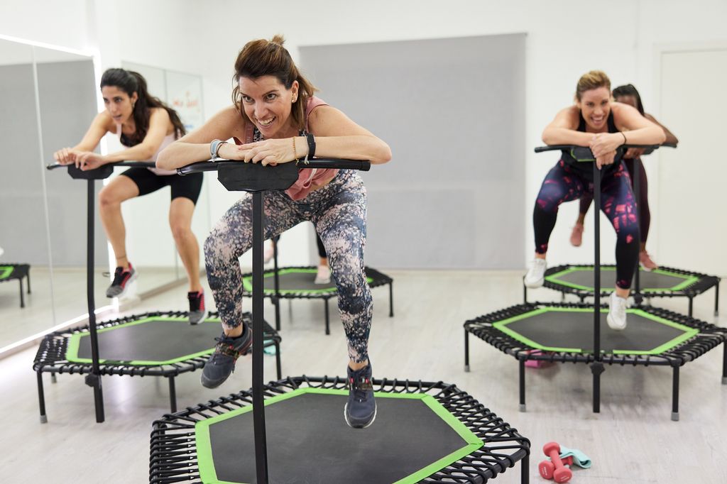 A middle-aged instructor jumping on a fitness trampoline.
