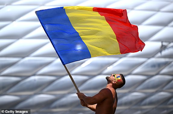 MUNICH, GERMANY - JUNE 17: A Romania fan waves a flag outside the stadium before the UEFA EURO 2024 group stage match between Romania and Ukraine at the Munich Football Arena on June 17, 2024 in Munich, Germany. (Photo: Sean Botterill/Getty Images)