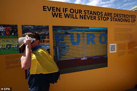 epa11417384 A man wearing VR glasses walks through an installation displaying damaged seats from Sonyachny Stadium in Kharkiv, Ukraine, at Wittelsbacherplatz in Munich, Germany, June 17, 2024. Ukraine was a co-host of the UEFA Euro 2012 football tournament and the stadium was damaged during shelling during the ongoing Russian invasion. The Ukrainian national team will face Romania in their UEFA Euro 2024 debut match on June 17 in Munich, Germany. EPA/ANNA SZILAGYI