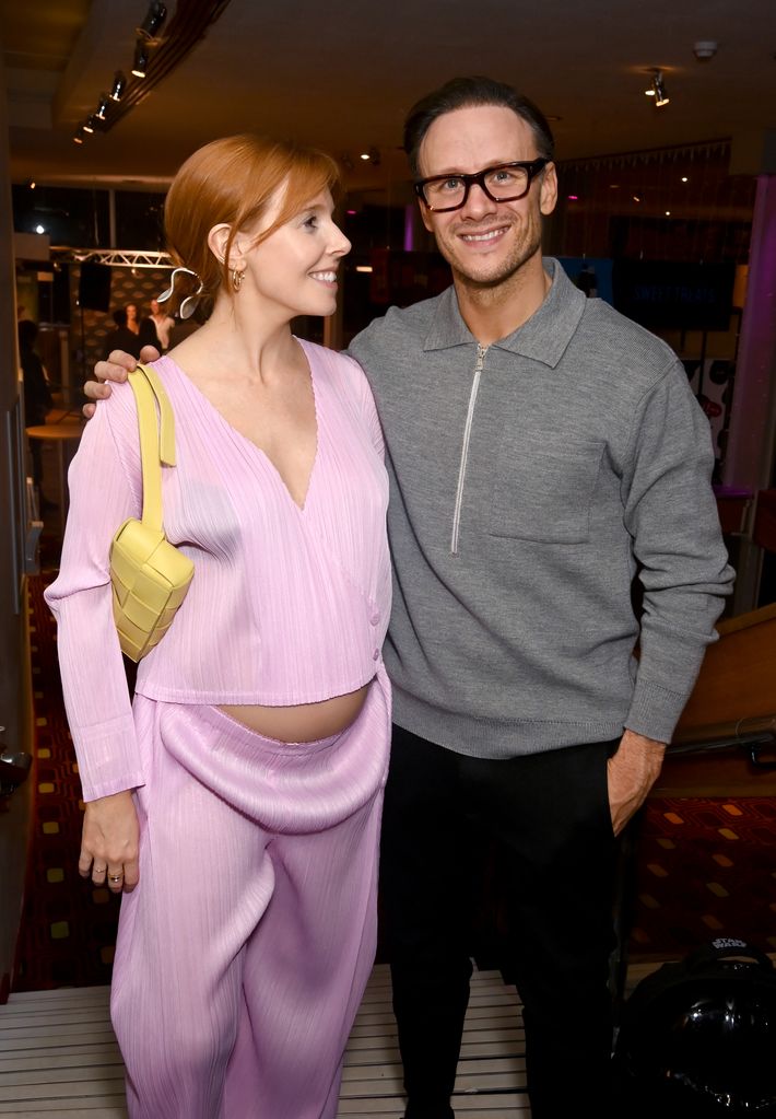 Stacey Dooley in a pink dress and Kevin Clifton in a grey jumper and trousers standing