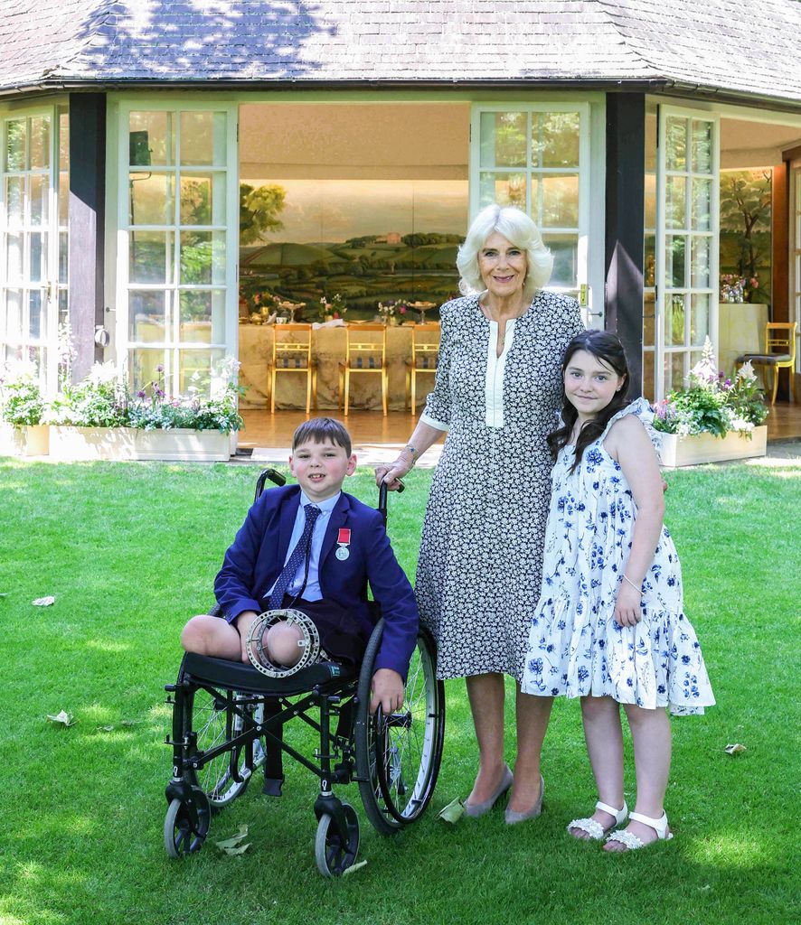 Queen Camilla with a young boy in a wheelchair and a young girl in a floral dress