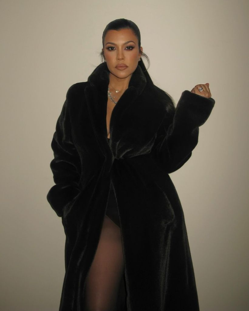 Kourtney Kardashian wearing a black leotard and fur coat