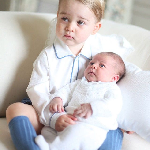 Prince George holds baby Princess Charlotte in his arms.