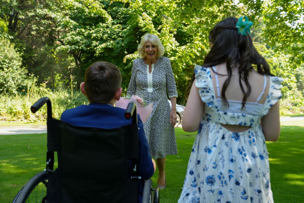 Queen Camilla greets a young girl and a young boy in a wheelchair