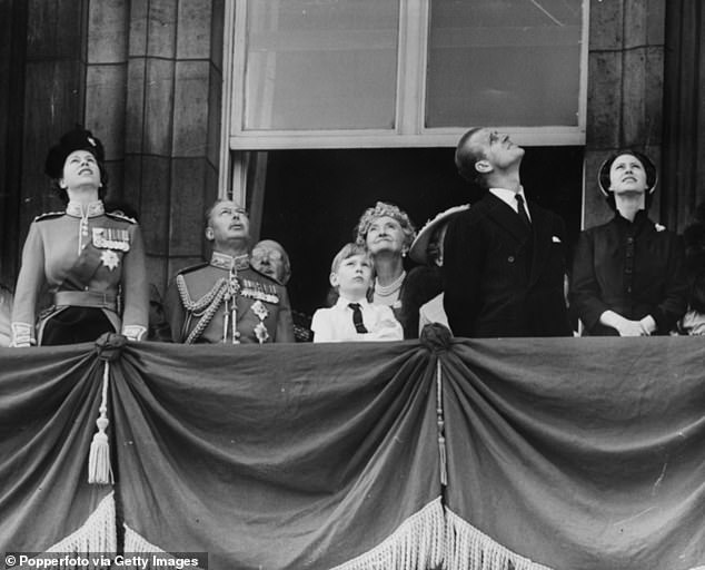 The British Royal Family look up from the balcony of Buckingham Palace to view a flypast
