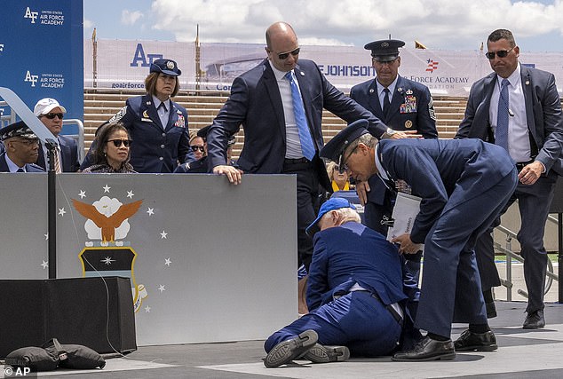 कोलोराडो में एयर फ़ोर्स अकादमी के ग्रेजुएशन समारोह में मंच पर गिरने के बाद बिडेन पीछे मुड़कर सैंडबैग की ओर देखते हुए