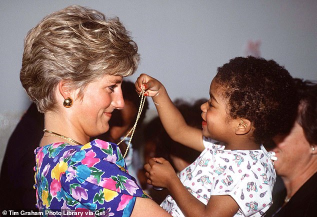 Princess Diana warmly holds a little girl in her arms as she plays with her necklace during a visit to a hostel for abandoned children in Sao Paulo, Brazil, in 1991