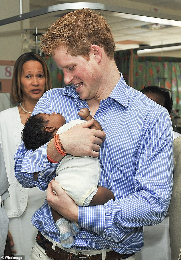 Prince Harry holding baby Jean-Luc Jordan during a visit to the children's ward at the Queen Elizabeth ll hospital in January 2010 in Bridgetown, Barbados