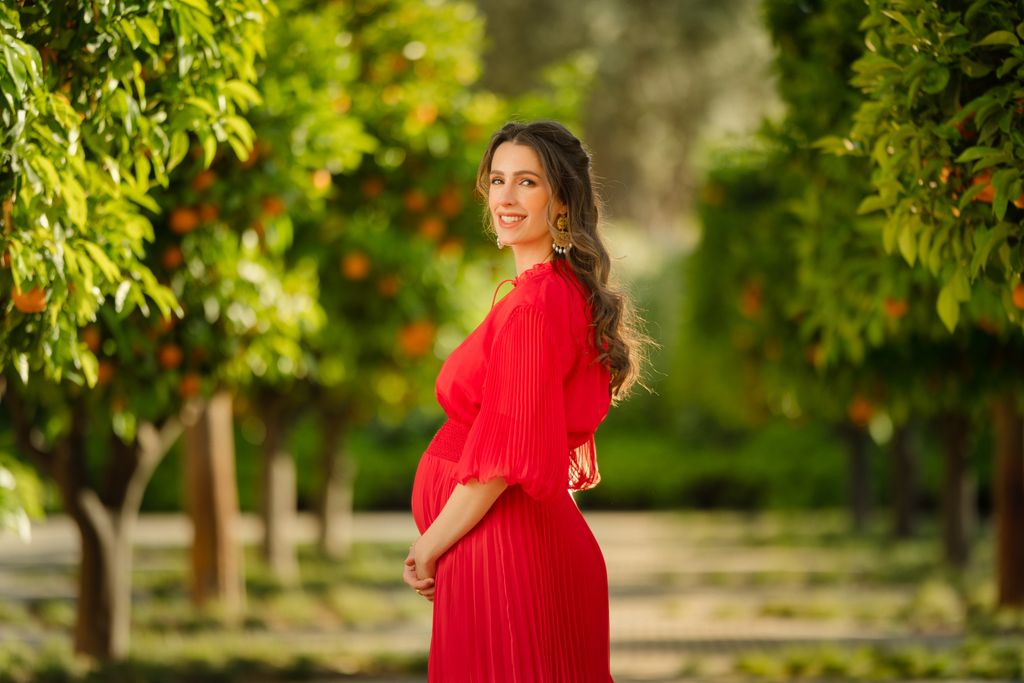 Princess Rajwa stands in a garden holding her fetus in her lap