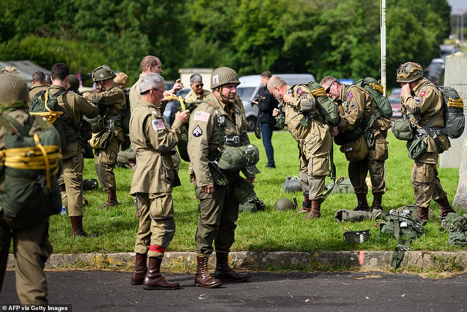 Parachutists wearing replica WWII-era paratrooper attire check their equipment prior to their jump from a Lockheed C-130 Hercules aircraft in Normandy today