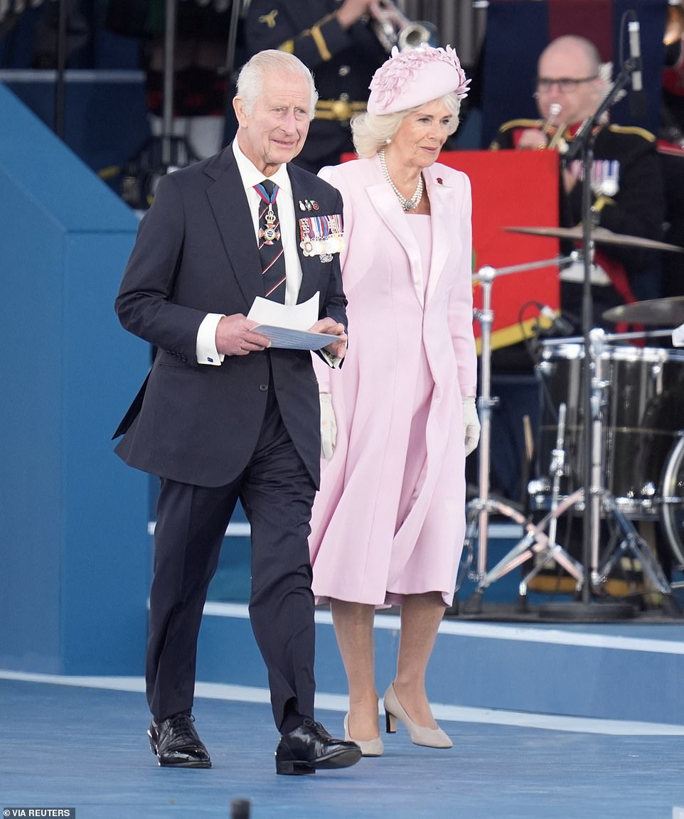 The King smiles as he walks onto the stage alongside Queen Camilla