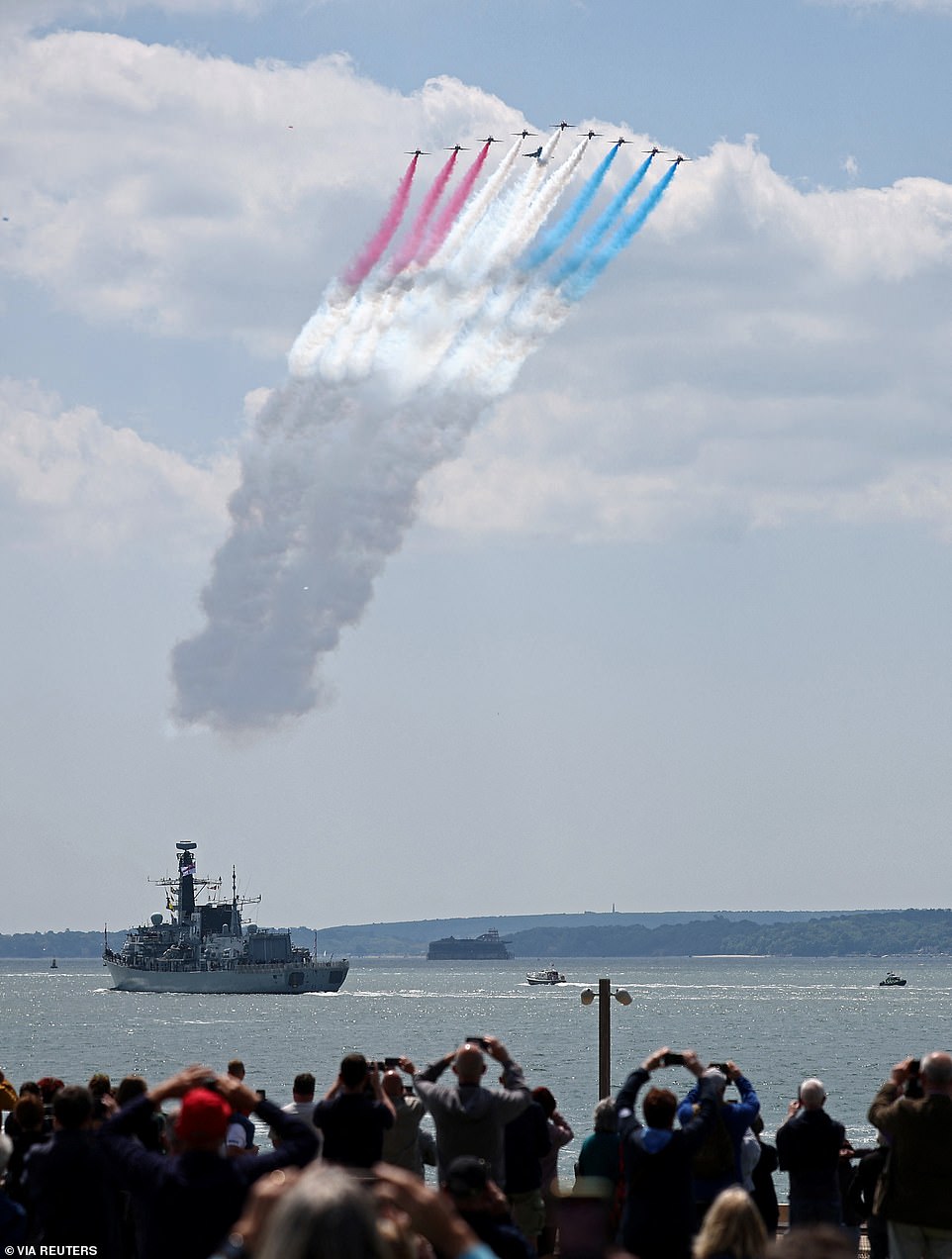Members of the public watch as the Red Arrows perform a flypast above HMS St Albans, a Type 23 Frigate