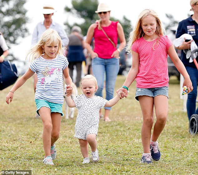 Isla Phillips (left) and Savannah Phillips (right) walking hand in hand with their cousin Lena Tindall in 2019