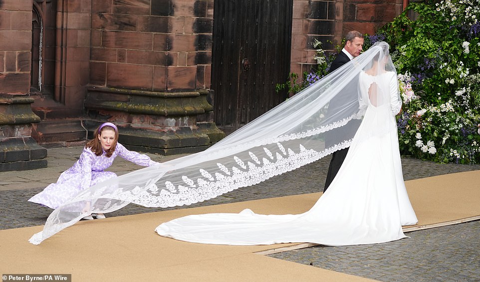 The bride stands in her wedding dress before entering the Cathedral in Cheshire