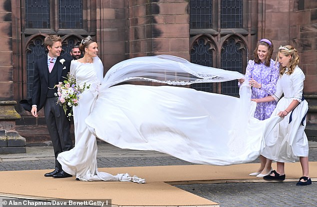 A bridesmaid and wedding dress designer Emma Victoria Payne struggle to keep Olivia's veil down in the wind