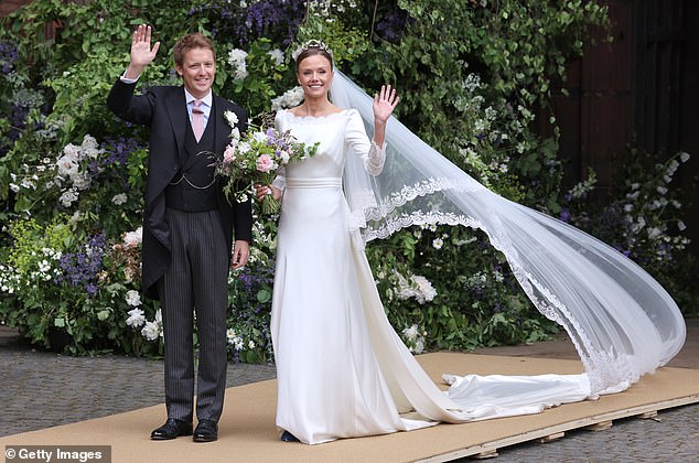 The bride's dress featured a cinched waist and a scalloped neckline as well as lace detailing on the sleeves