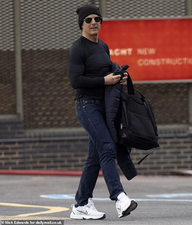 Tom Cruise, 61, shows off his muscle-bound physique in a skintight top as he lands at a London Heliport to film Mission: Impossible 8