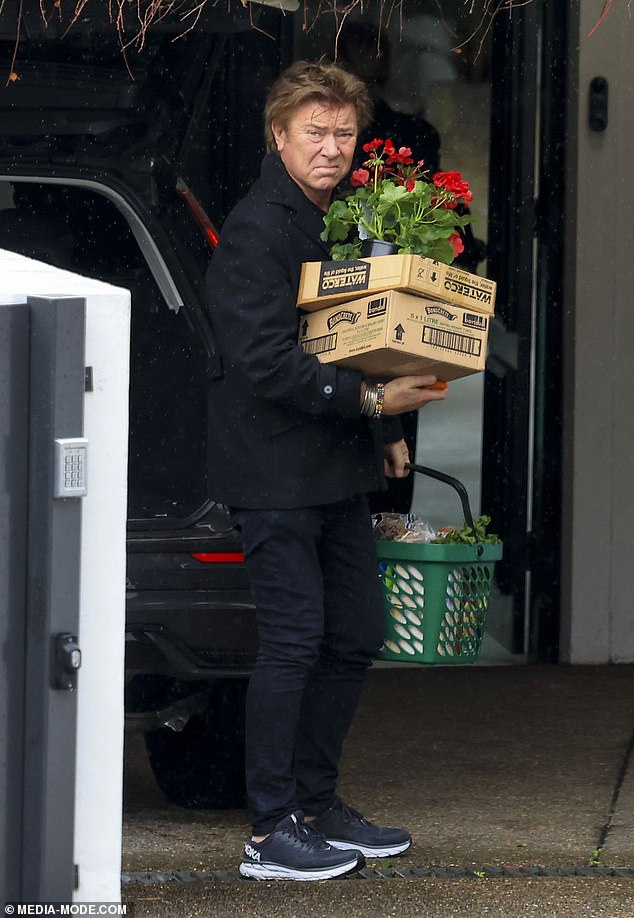 Richard Wilkins uses a Woolworths basket to carry his groceries into his home after a shopping trip with his girlfriend Mia Hawkswell