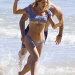 Bachelorette star Ali Oetjen appears to reveal her boob job scar as she has a wardrobe malfunction in a tiny bikini while frolicking on the beach in with beau Mitch Adams