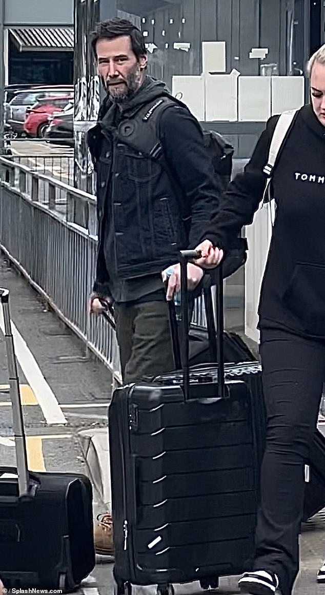 Keanu Reeves, 59, looked very comfortable when he arrived in Manchester, England on Monday. The actor wore a slate blue hoodie and khaki green pants and a denim jacket. He was carrying a gray backpack and a large suitcase