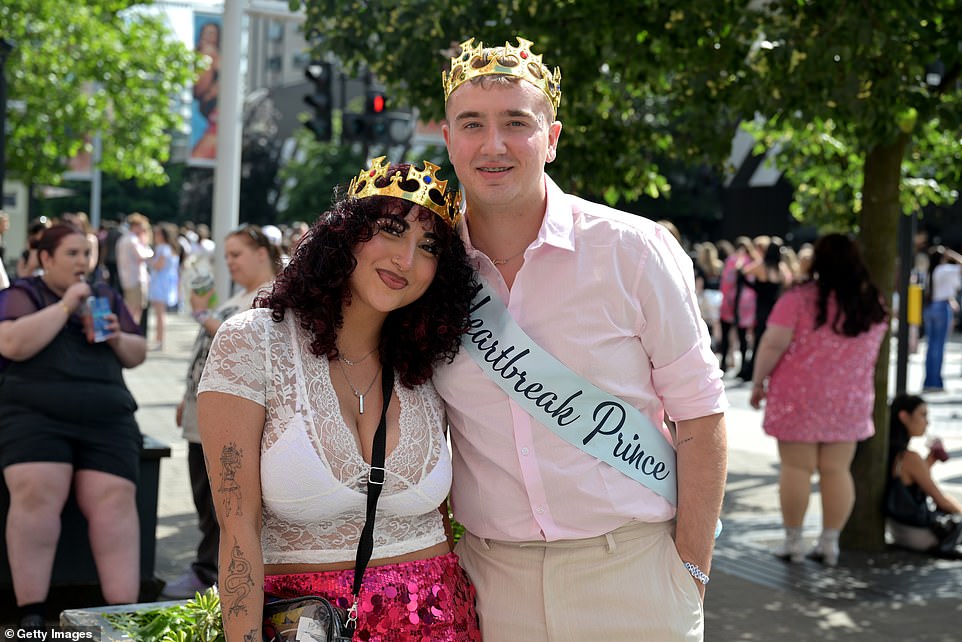 A pair of fans wear crowns and a sash that reads 'Heartbreak Prince' referring to Swift's song 'Miss Americana and The Heartbreak Prince' from her 2019 album Lover