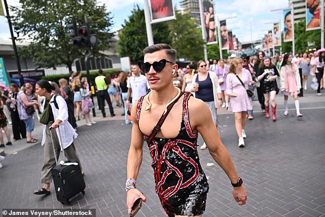 A male Swiftie wearing a snake necklace and black love heart sunglasses arrives at Wembley Stadium ahead of the concert today