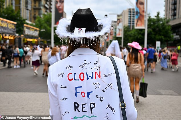 A Taylor Swift fan wears a cowboy hat and a jacket with the word 'Clown for Rep' written on the back outside Wembley today