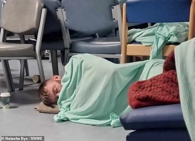 A man sleeps on the floor while waiting in A&E at William Harvey Hospital in Ashford, Kent