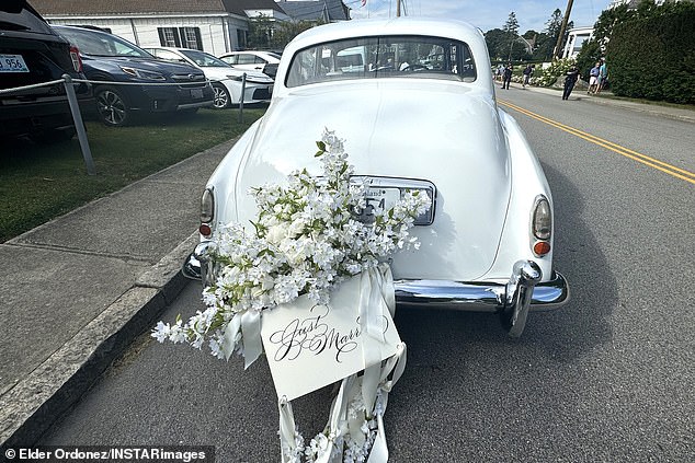 A bouquet of flowers and a wedding card are placed in the back of the car
