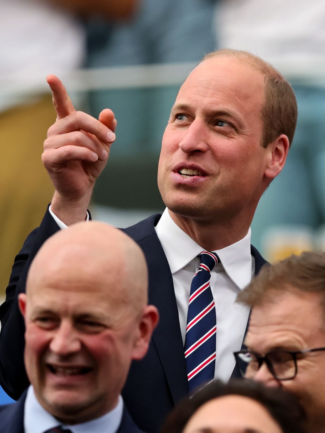 Prince William stands and gestures with King Frederick during a football match