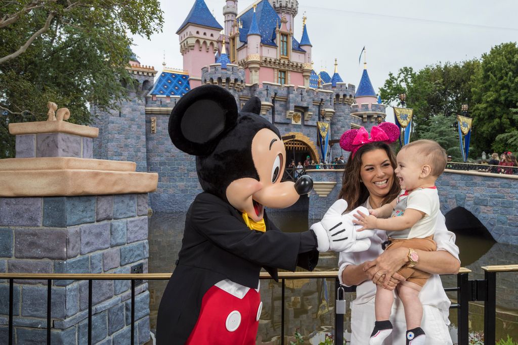 Eva Longoria holds a baby boy who is greeted by Mickey Mouse