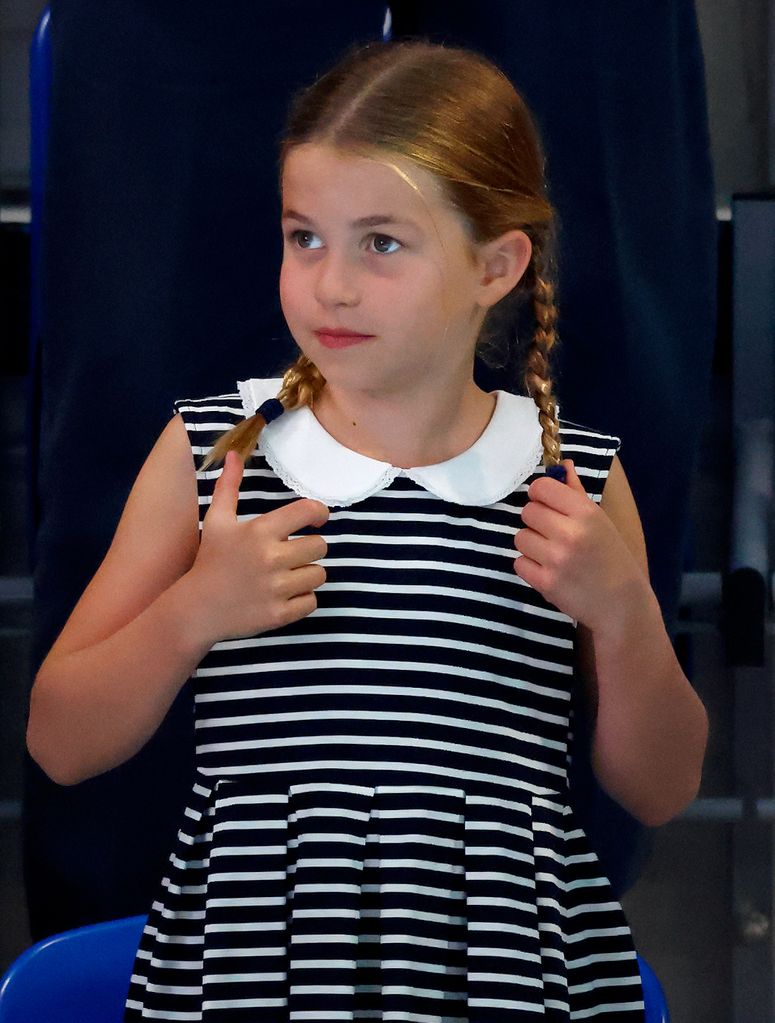 Princess Charlotte in a striped dress with her hair tied in braids