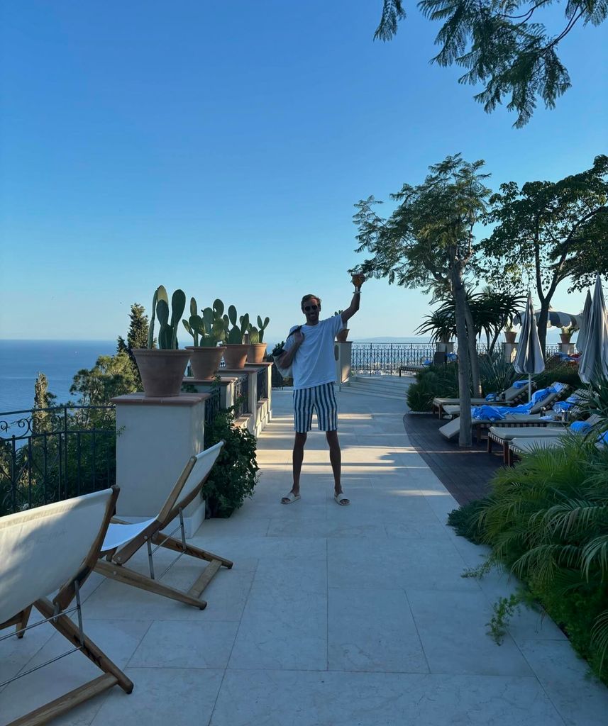 Peter Crouch in shorts waves from a balcony in Sicily 