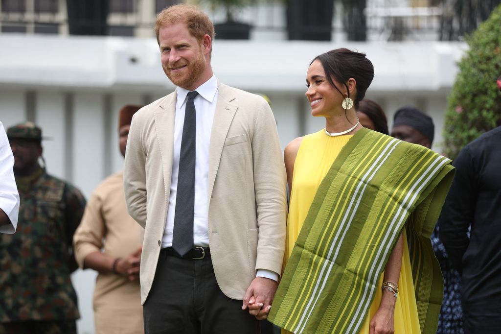 Britain's Prince Harry (II), Duke of Sussex, and Britain's Meghan (right), Duchess of Sussex, react to a speech by Lagos State Governor, Babajide Sanwo-Olu (invisible), who delivers a speech at the state governor's house in Lagos on May 12, 2024, when they visit Nigeria as part of the Invictus Games anniversary celebrations.