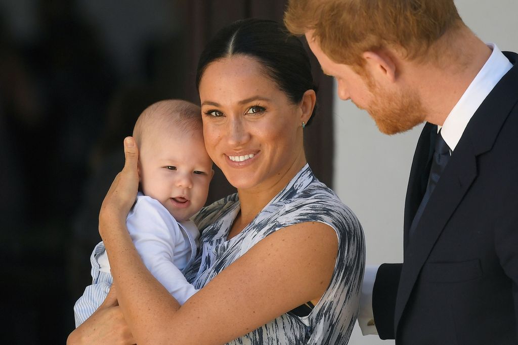 Meghan Markle holds Archie in her arms as Harry looks at her lovingly