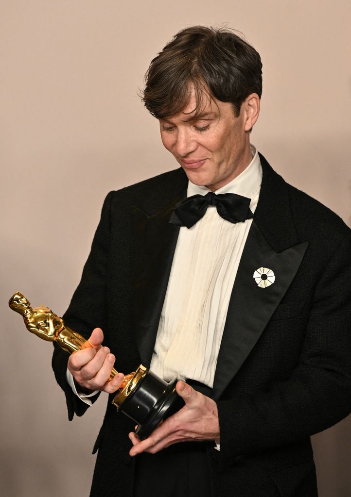 Irish actor Cillian Murphy looking at his Oscar while being photographed in the press room