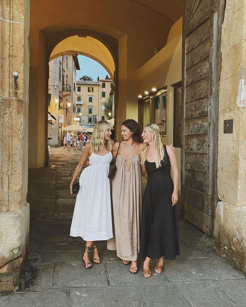 Three women wearing summer clothes standing at an archway