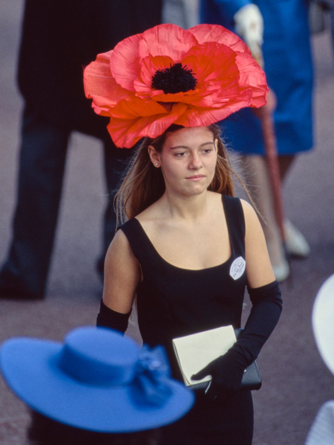A female racegoer wearing a black dress, black gloves and a red poppy hat on the first day of Royal Ascot on June 19, 1990.