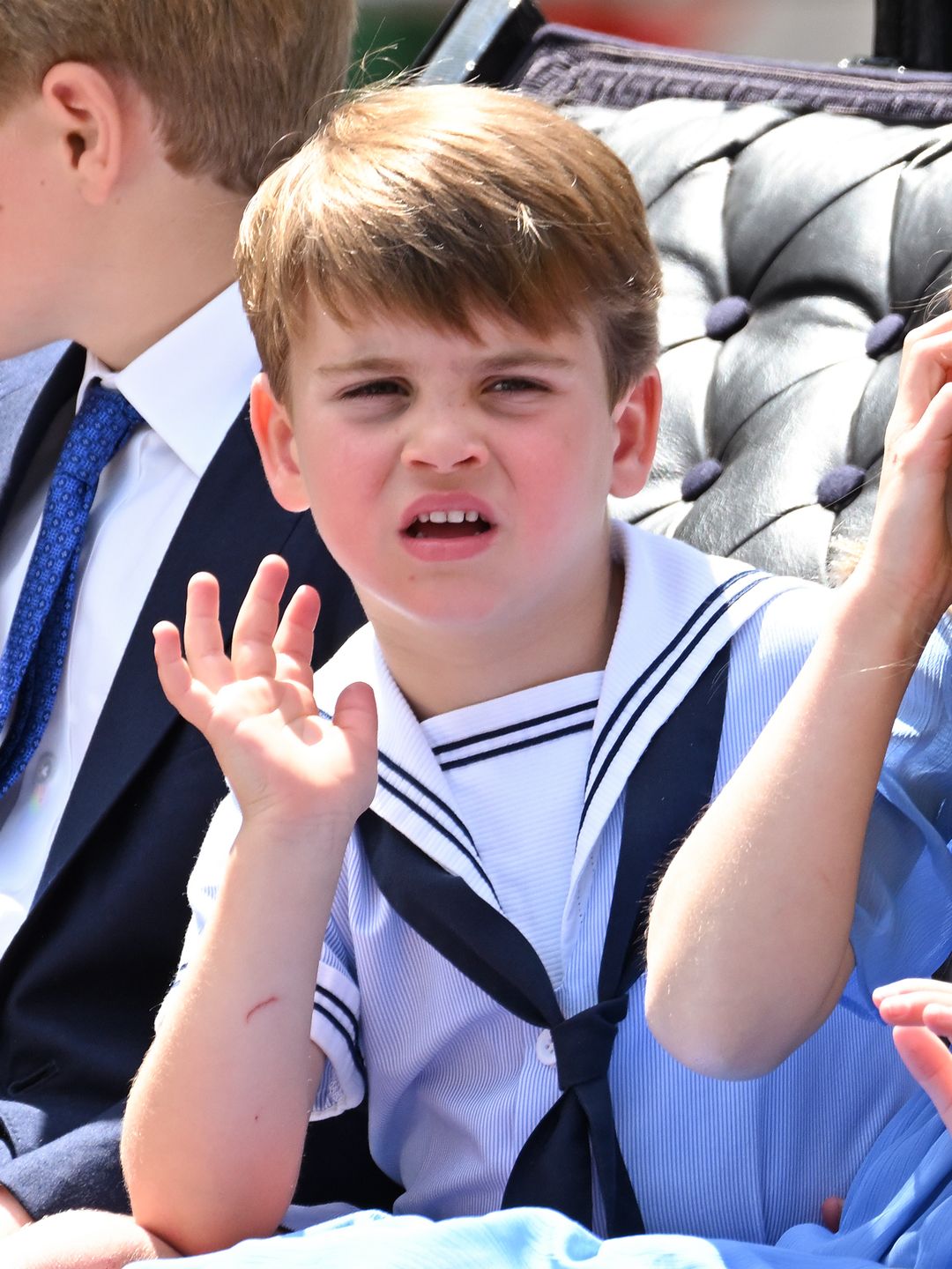 Prince Louis waves while dressed in a sailor's uniform