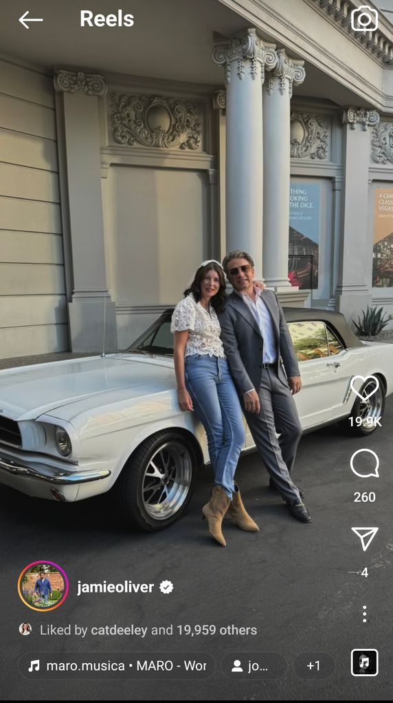 couple leaning against old white car