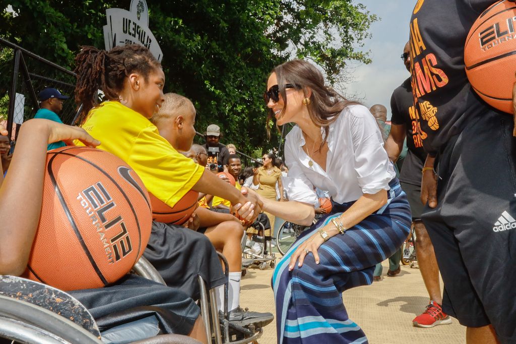 Meghan Markle holds a child's hand during Giants of Africa at Ilupeju Senior Grammar School