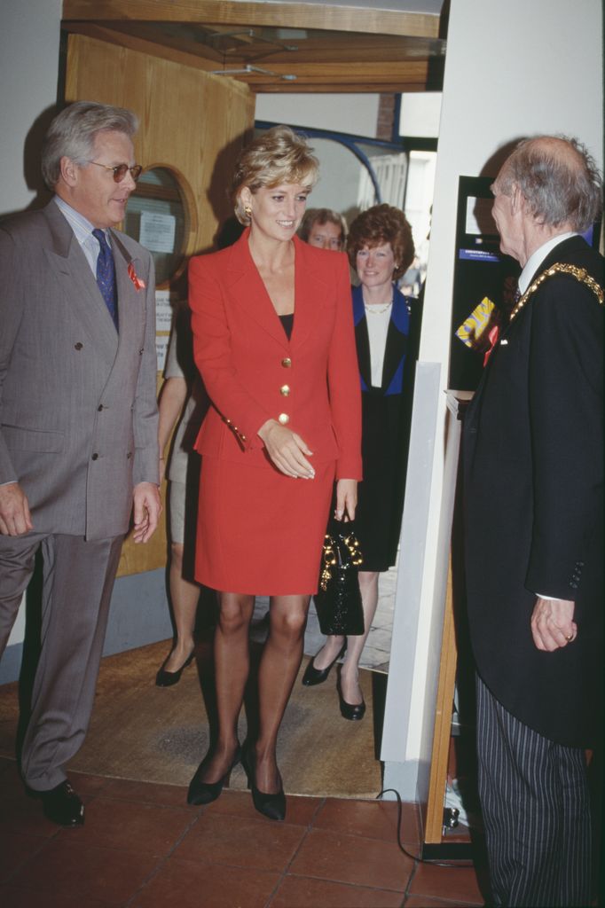Princess Diana in a red suit meeting people at the London Lighthouse